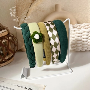 Detail view of five assorted green knitted headbands with diverse textures and patterns