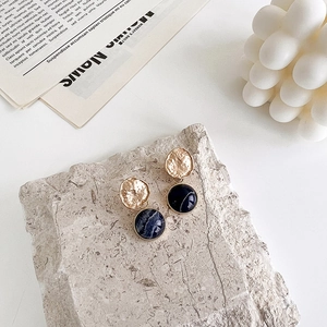 Detail of vintage gold earrings with irregular texture and dark blue resin inlay