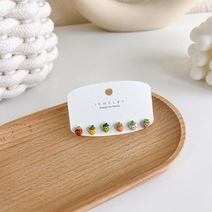 Close-up of colorful 925 silver strawberry stud earrings set on a wooden tray