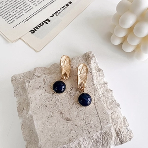 Detailed close-up of vintage Klein blue round drop earrings on a grey stone base