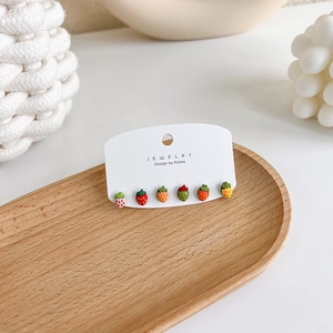 Close-up of six colorful strawberry stud earrings set on a jewelry display card