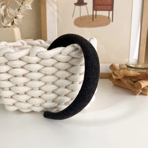 Close-up of black thickened hairband with wool texture on a stylish woven basket