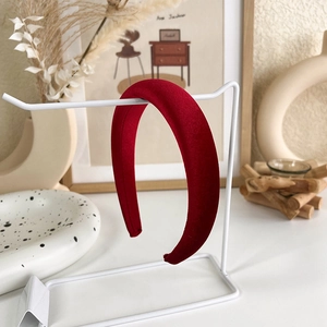 Gros plan détaillé d'un serre-tête épais en velours rouge sur un support minimaliste