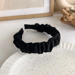 Close-up of black ruched velvet headband texture on elegant white decorative plate