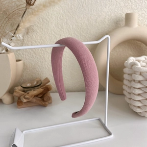Macro detail of pink knitted sponge headband texture on a minimalist display stand