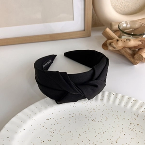 Detailed close-up of woven black knotted headband featuring a white handmade label