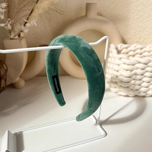 Detail of dark green velvet padded headband with a handmade label on a vintage stand
