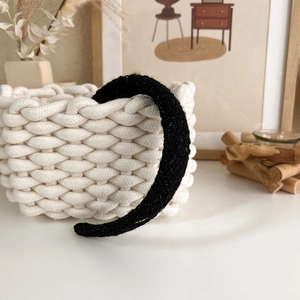 Close-up of black headband with golden glitter texture on a woven storage basket