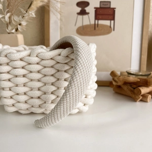 Detail of a beige padded headband with diagonal knit texture on a woven basket