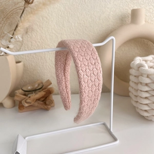 Detailed view of pink knitted headband featuring honeycomb texture on a display stand