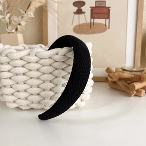 Close-up of black plaid headband with a thick knitted texture on a woven basket
