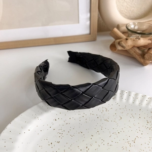 Close-up of elegant black faux leather braided texture on a high-top knitted headband