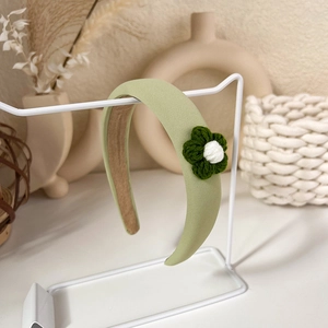 Close-up of a green padded headband featuring hand-knitted flower details and non-slip lining