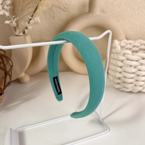 Detail of the lake green knitted headband showing the handmade label and soft texture