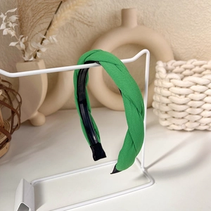 Close-up of green braided headband on white display stand with elegant home decor
