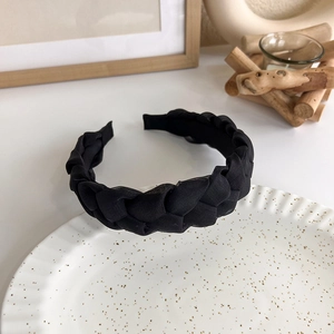 Detail of elegant black braided headband with texture on a white decorative plate