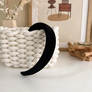 Detail of a thick black velvet headband displayed on a woven basket in a cozy home setting