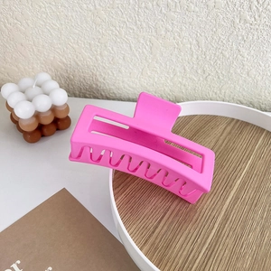 Detail view of a matte hot pink square hair claw clip on a stylish decorative tray