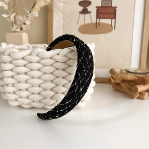 Close-up of black and white tweed headband with silver thread on a woven basket