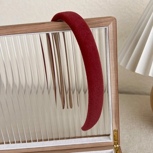 Close-up of thick burgundy velvet headband on a textured glass display for luxury texture