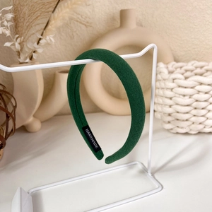 Detail of dark green fabric headband with handmade label in a cozy aesthetic setting