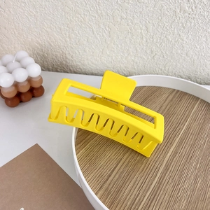 Macro shot of large matte yellow hair claw clip with a hollow rectangular design