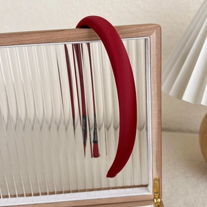 Deep red velvet headband shown on a textured glass display with a warm artistic vibe