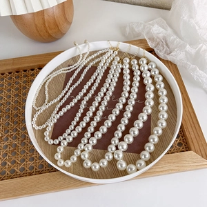 Detail showing various sizes of lustrous pearl necklaces with golden metal clasps and chain