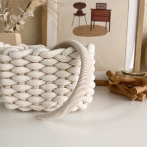 Detailed view of beige woven headband with knitted texture on cream storage basket