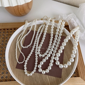 Detail view of various sizes of creamy white pearl necklaces with golden lobster clasps