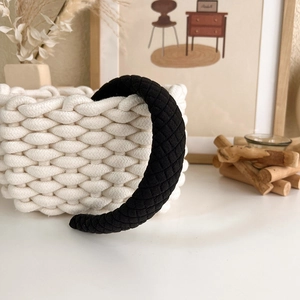 Close-up of black quilted headband with thick diamond texture on a warm aesthetic background