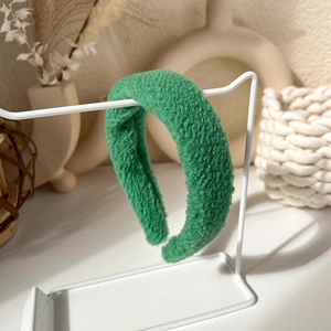 Close-up of grass green fleece headband with thick texture on white metal display stand