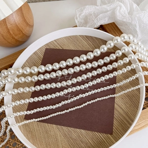 Detail showing different sizes of creamy white pearls with warm luster on wood texture