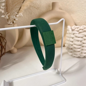Detail showing deep green padded headband with vintage square silicone logo on display