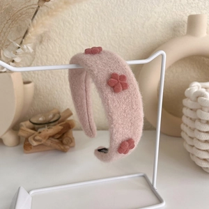 Detailed close-up of pink plush headband featuring three red floral decorations and soft texture
