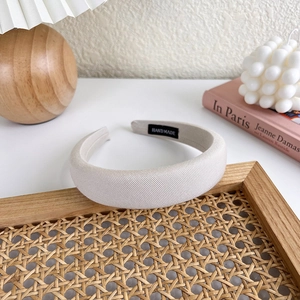 Detail der Textur des cremefarbenen Schwamm-Stirnbands mit handgefertigtem Etikett