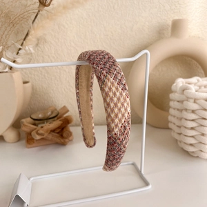 Detail of tweed sponge headband with multi-color woven texture on white display stand