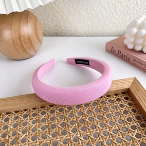 Detailansicht eines gepolsterten rosa Haarreifens mit handgemachtem Etikett und Textur