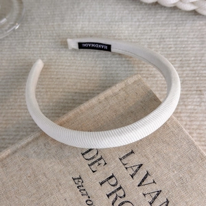 Detail of cream ribbed headband featuring a black Handmade woven label on the inner side