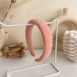 Detail showing the soft pleated fabric texture of the pink padded headband on a stand