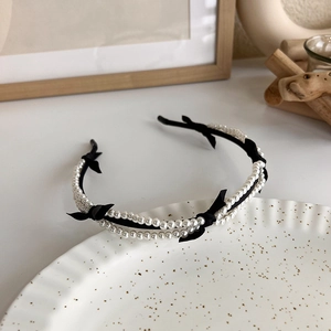 Detail of double-row pearls and black bows on a knitted headband for a sweet French style