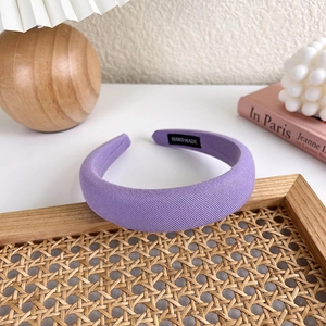 Detail eines hellvioletten Schwammstirnbands mit Twill-Struktur und handgefertigtem Etikett