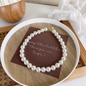 Detailed view of glossy white pearls on a necklace with adjustable golden lobster clasp