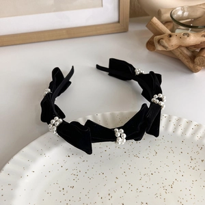 Detail of black velvet headband featuring five bows and elegant pearl ring ornaments