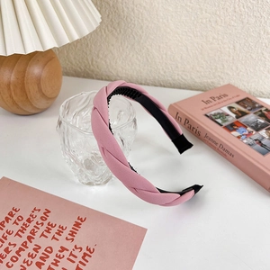 Detail of pink woven fabric headband with inner grip teeth on white aesthetic desk