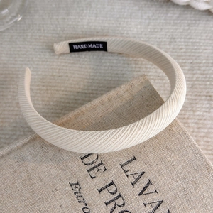 Detail of handmade wide cream headband with textured fabric on rustic linen background