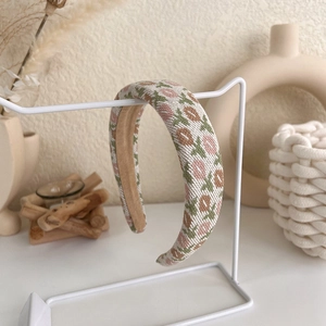 Detail of pink floral knitted headband with padded sponge on a display stand