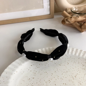 Detail of black velvet braided headband with white pearls and gold dots on display