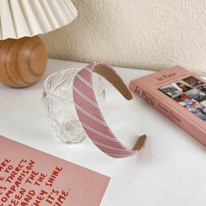 Detailed view of pink striped fabric headband displayed on a glass cup with props