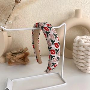 Detail of pink tulip knitted headband with soft brown velvet lining on minimalist stand